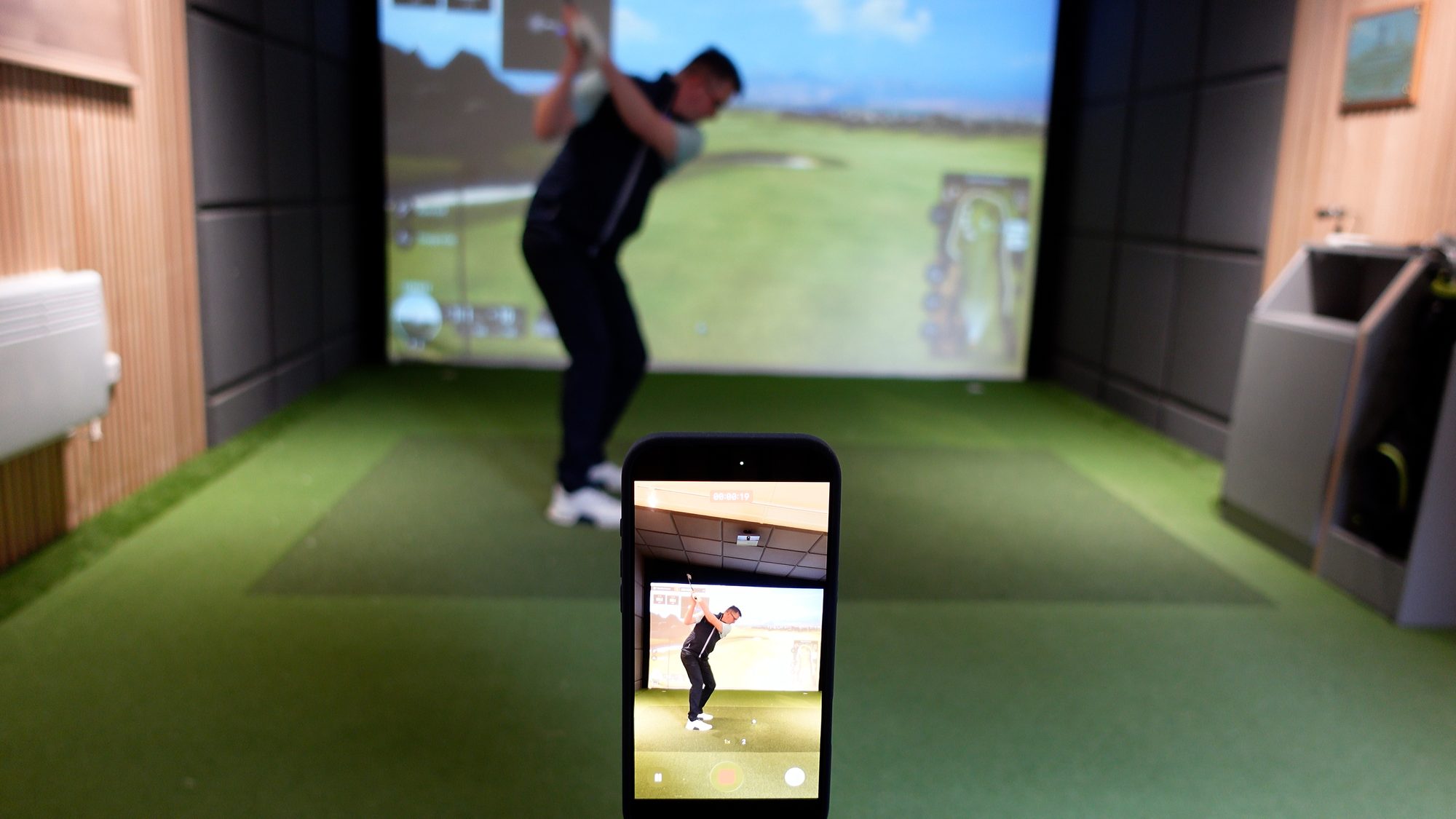 Golfer filming a swing on a phone for online golf coaching